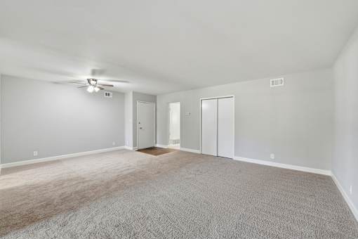 A spacious room with a ceiling fan and carpeted floor.