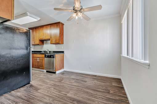 A kitchen with a black refrigerator and wooden cabinets.