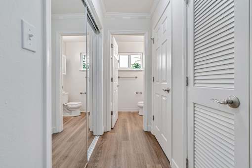 A white hallway with wood floors and white doors.
