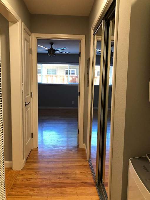 A hallway with a ceiling fan and sliding glass doors.