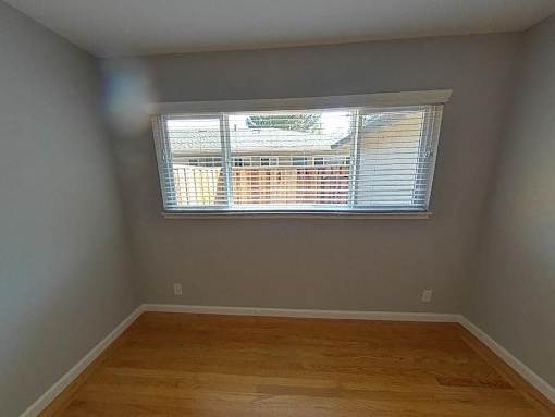 A room with a window and wooden flooring.
