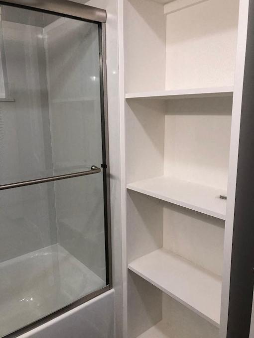A white shelving unit with a glass door.