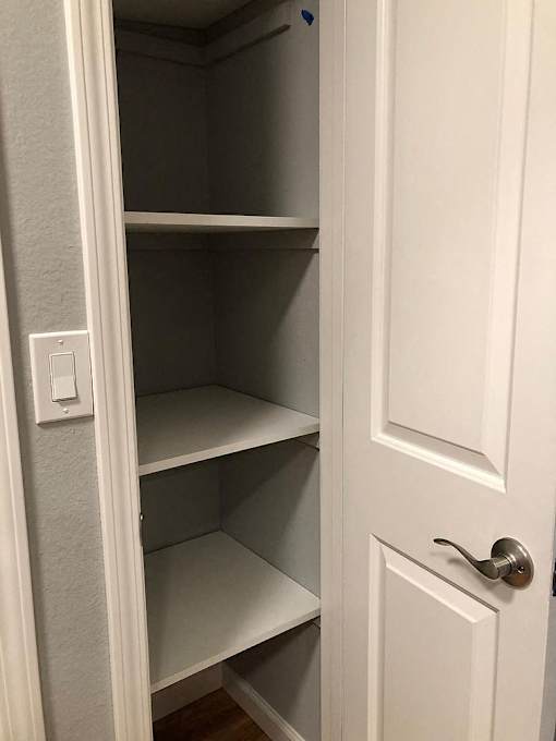 A white door with a silver handle and a white light switch on the wall.