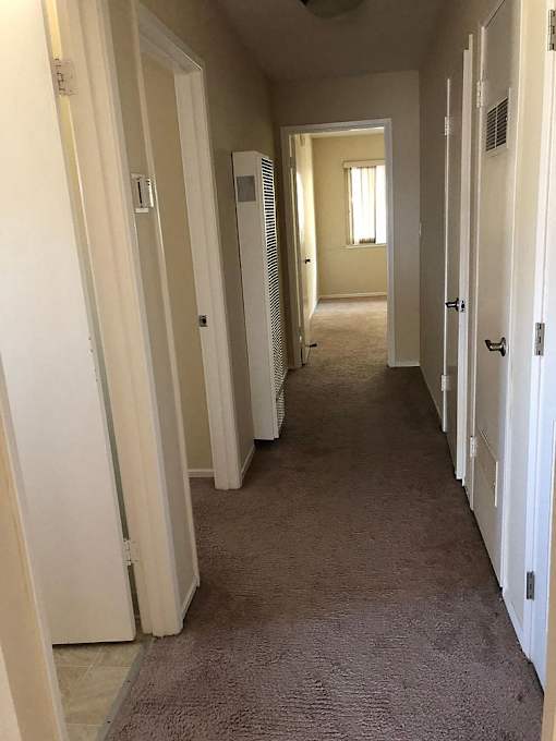A long hallway with white doors on both sides.
