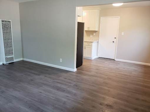 A kitchen with a black refrigerator and white cabinets.