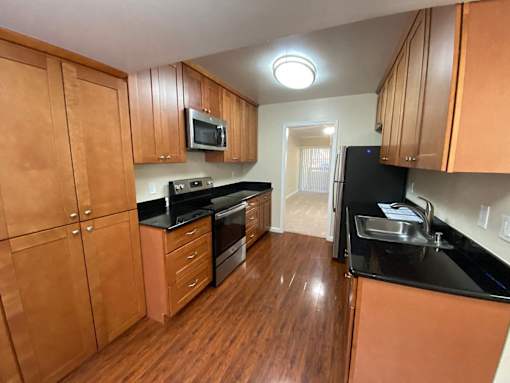 A kitchen with wooden cabinets and black countertops.