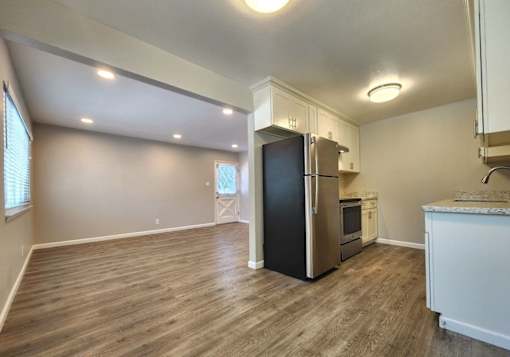 A kitchen with a black fridge and wooden floors.