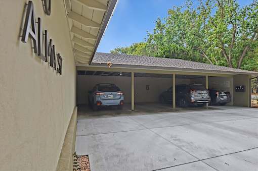 A carport with three cars parked in it.
