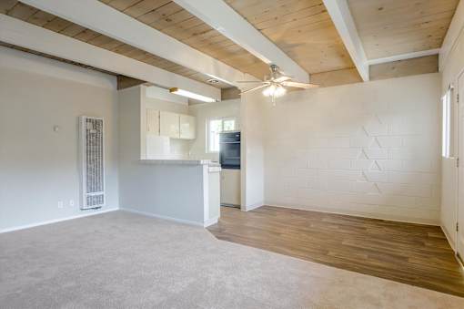 A spacious room with wooden floors and a ceiling fan.