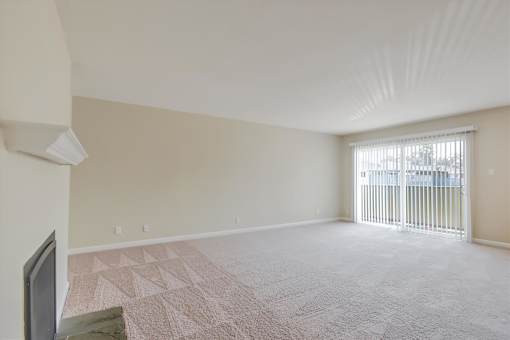 A room with a carpeted floor and a window with blinds.