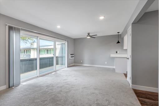 an empty living room with sliding glass doors to a balcony