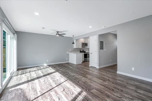 a living room with a kitchen and a ceiling fan