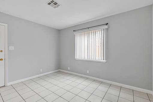 A room with a white tile floor and a window with blinds.