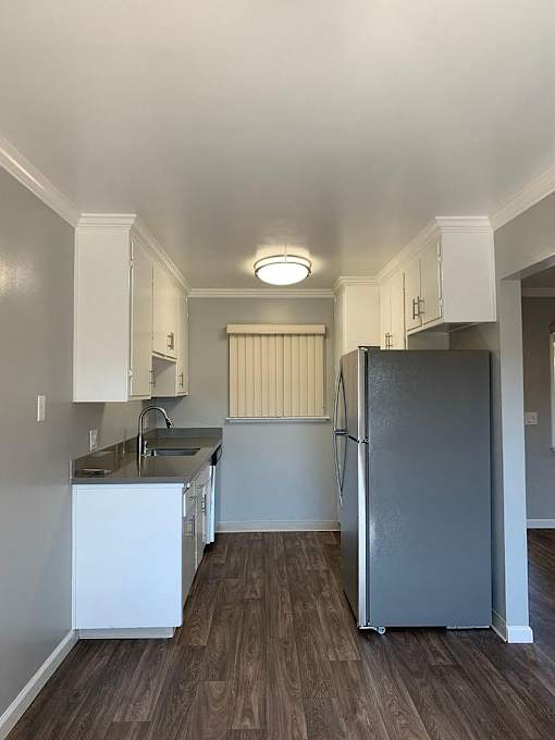 A kitchen with a refrigerator, sink, and cabinets.