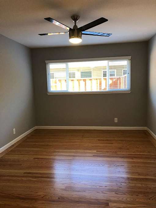 A room with a ceiling fan and a window.