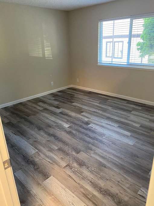 A room with a window and wooden flooring.