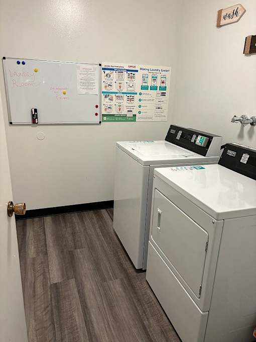 A laundry room with a whiteboard and a washer and dryer.