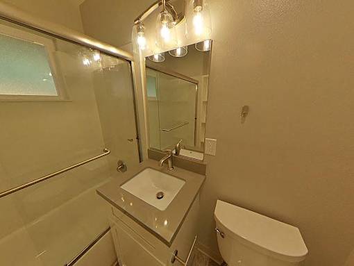 A bathroom with a sink, toilet, and mirror.