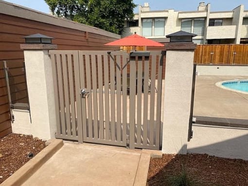a fence with a red umbrella in front of a pool