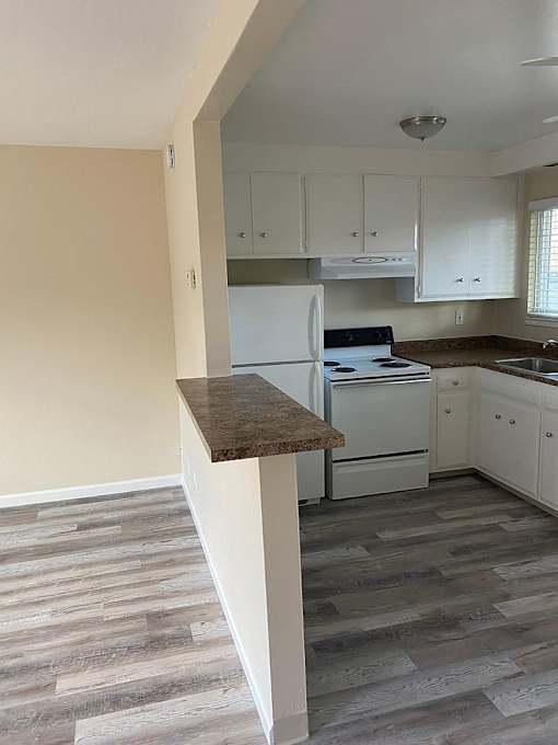 A kitchen with a white fridge and cabinets.