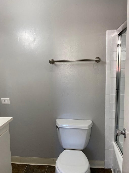 A white toilet in a bathroom with a white cabinet and a glass shower door.