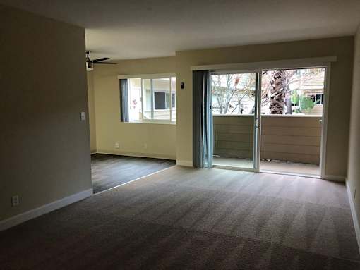 A room with a carpeted floor and a ceiling fan.