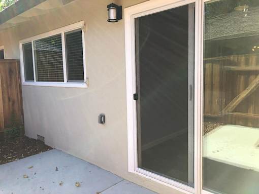 A white door with a black handle is on the side of a house.