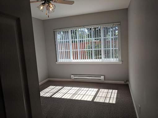 A room with a window covered by white blinds and a ceiling fan.