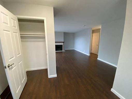 an empty living room with wood flooring and a closet