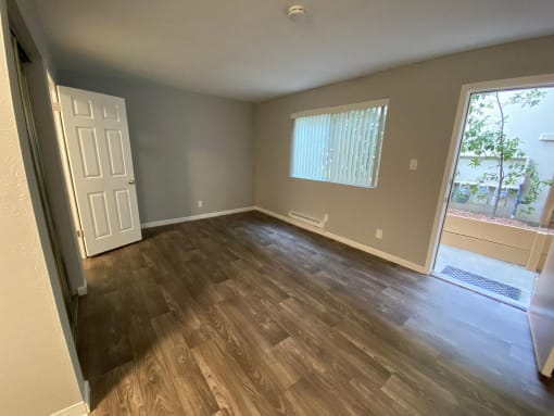 an empty living room with wooden floors and a window