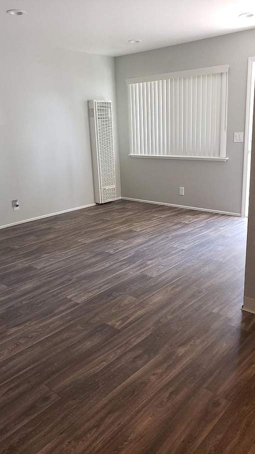 A room with wooden flooring and a window with blinds.