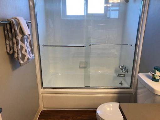A white toilet sits in a bathroom with a glass shower door.