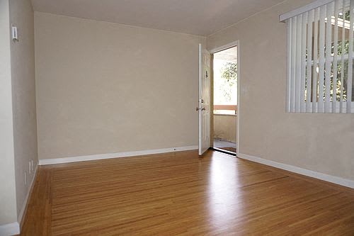 A room with wooden floors and a door leading to a balcony.