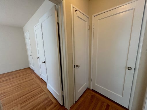 a bedroom with three closets and a hard wood floor