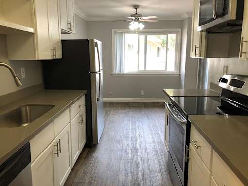 A kitchen with black appliances and white cabinets.