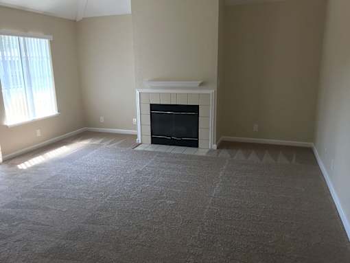 A living room with a fireplace and a carpeted floor.