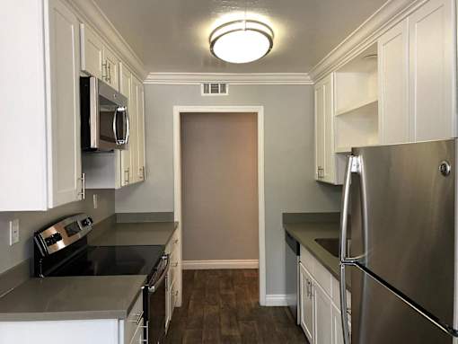 A kitchen with white cabinets and a stainless steel refrigerator.