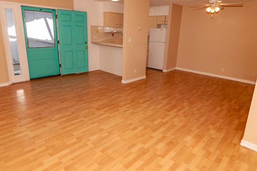 an empty living room with a wood floor and a green door