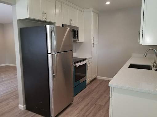 A kitchen with a black refrigerator and white cabinets.