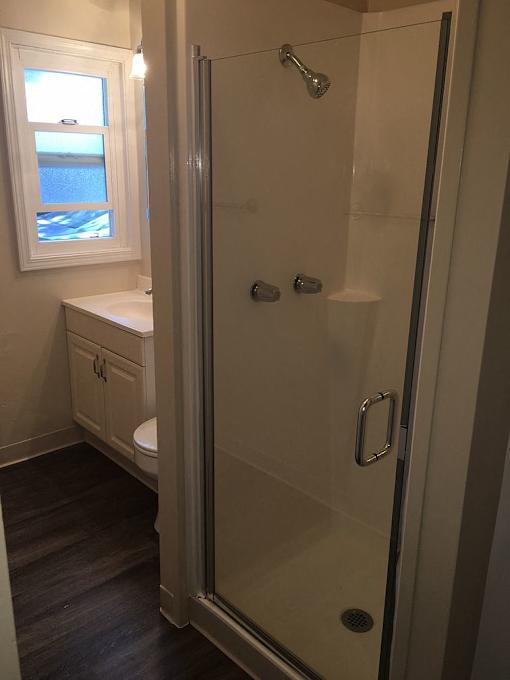 A bathroom with a walk in shower and a window.