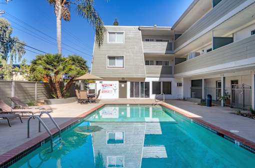 the pool is in front of a condo building with a swimming pool