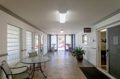 a dining room with a glass table and chairs and a hallway with doors and windows