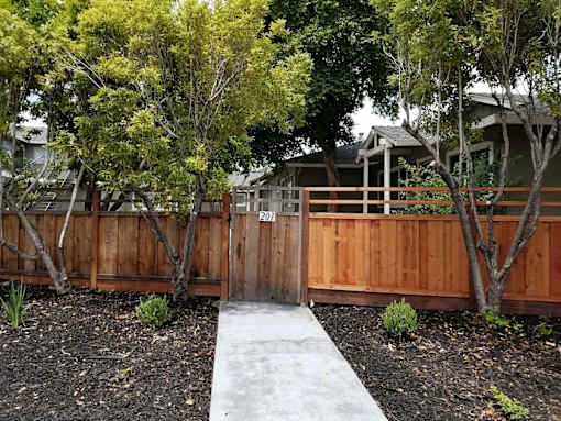A wooden fence with a gate in the middle of a garden.