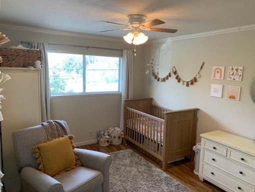 a nursery with a baby crib and a ceiling fan