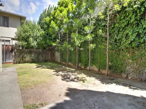 the backyard of a house with a fence and trees