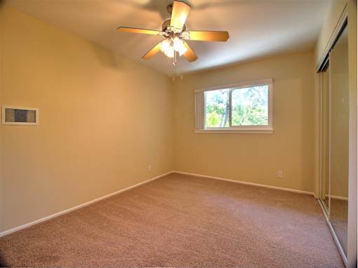 A room with a ceiling fan and a window.