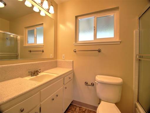 A bathroom with a toilet, sink, and mirror.