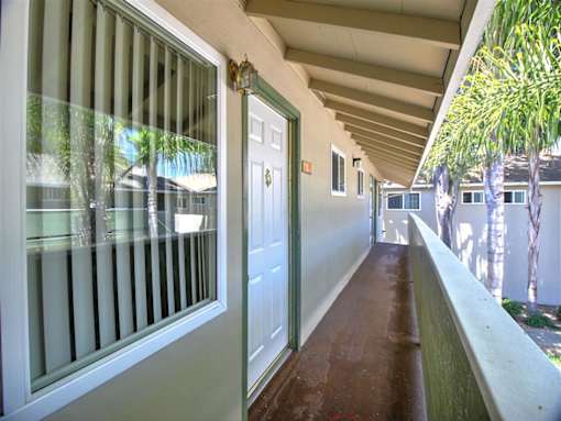 A long hallway with a white door and a window with blinds.