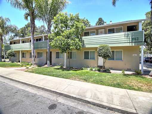 A row of houses with green lawns and trees.