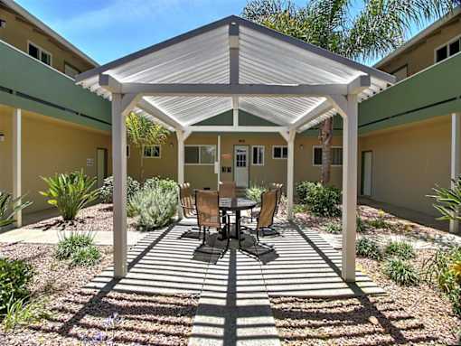 A patio with a table and chairs under a white roof.